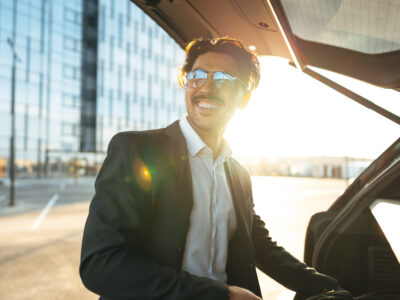 Successful businessman taking luggage from the car trunk