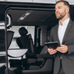 smiling-friendly-car-seller-in-suit-standing-in-ca-2024-08-27-04-05-29-utc (1)