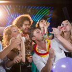 group-of-smiling-friends-blowing-party-horn-in-bar-2026-01-11-10-30-52-utc