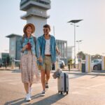Happy couple with passports and suitcase going to airport terminal. Copy space.